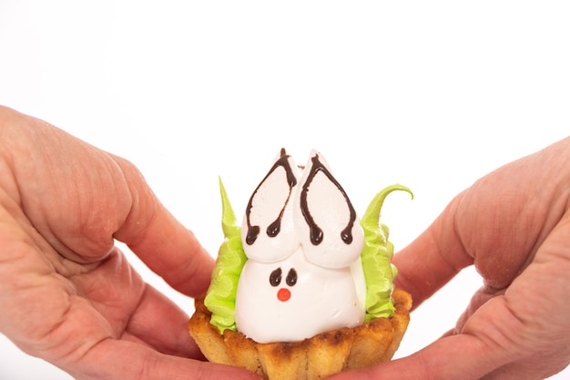 Mains tenant un gâteau protéiné fait maison en forme de lapin de Pâques allongé sur un biscuit comme dans un nid