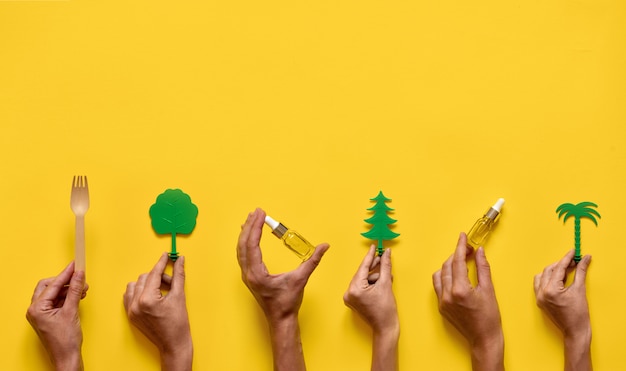 Photo mains tenant des huiles essentielles et des arbres. médecine naturelle plat poser. jaune