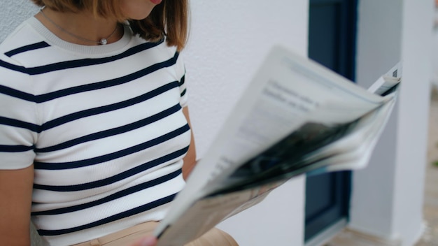 Mains tenant le journal du matin en gros plan sur une fille touristique concentrée lisant un magazine