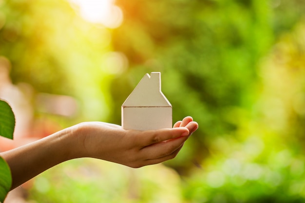 Mains tenant le modèle de maison en bois. Achat d&#39;un nouveau concept d&#39;assurance habitation et habitation.