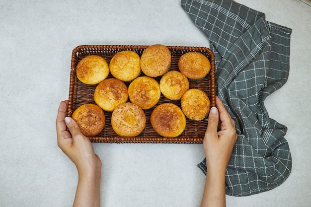 mains tenant un panier de muffins à la vanille et aux noix de caramel dans des gobelets en papier