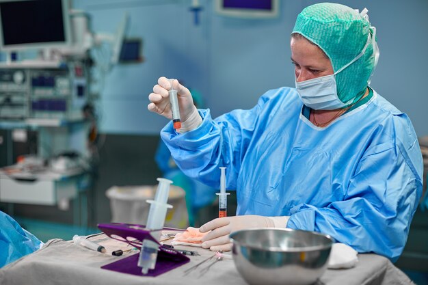 Mains tenant la seringue et transférer la graisse avec l'outil de transfert de graisse nano dans la salle d'opération