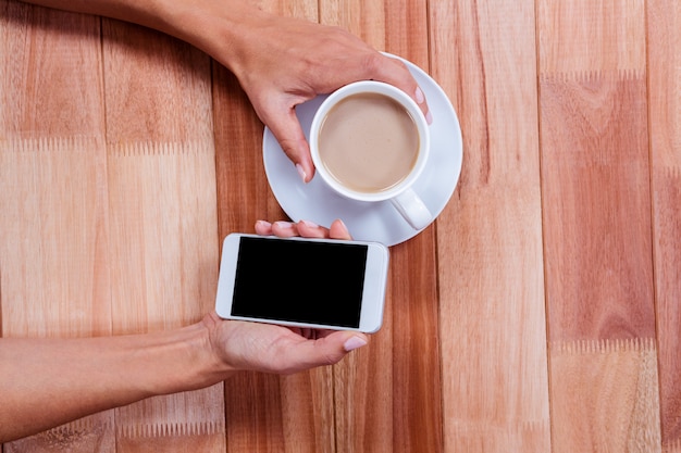 Mains tenant le smartphone et le café