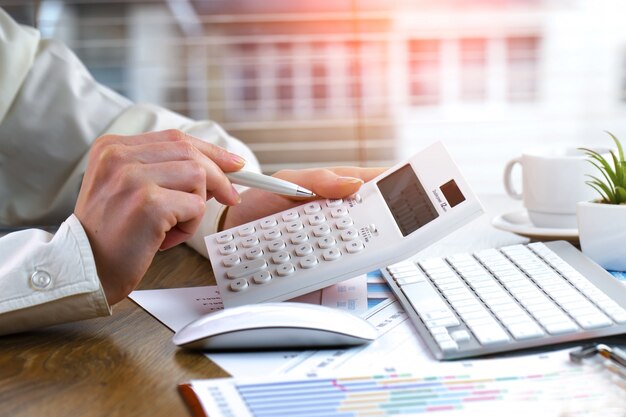 Mains tenant un stylo et une calculatrice