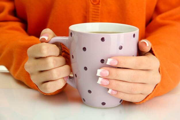 Mains tenant une tasse de boisson chaude en gros plan