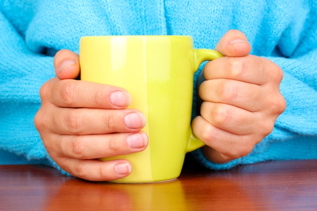 Mains tenant une tasse de boisson chaude, gros plan