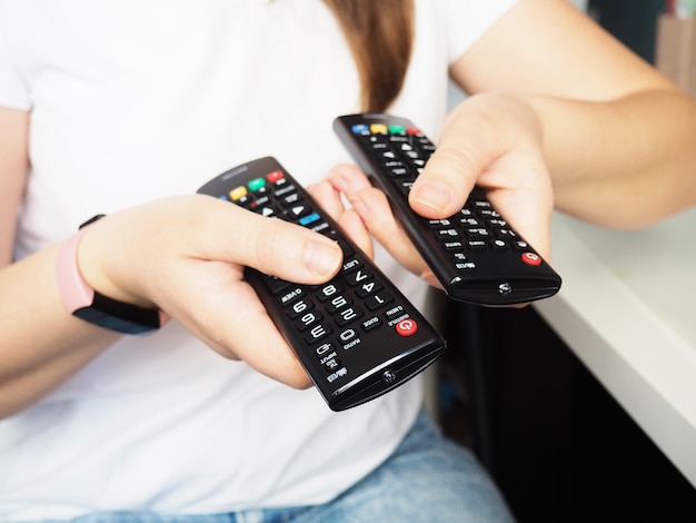 Mains tenant la télécommande du téléviseur, gros plan à la maison.