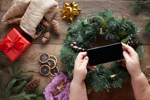 mains tenant un téléphone sur guirlande de Noël sur fond de bois