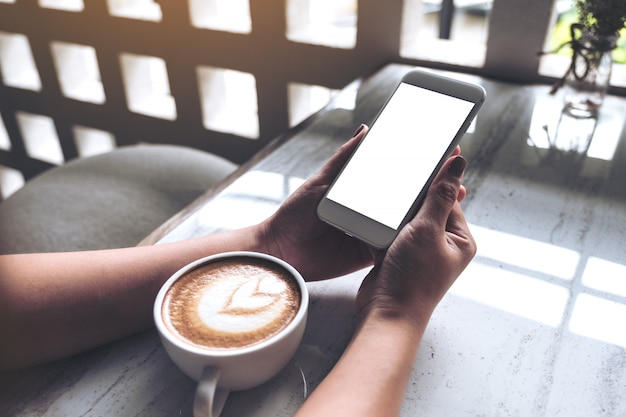 Mains tenant un téléphone mobile blanc avec écran de bureau vide