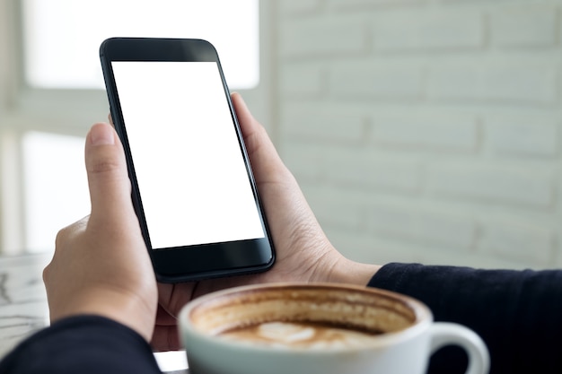 Mains Tenant Un Téléphone Portable Noir Avec écran Blanc Vierge Avec Une Tasse De Café Au Café