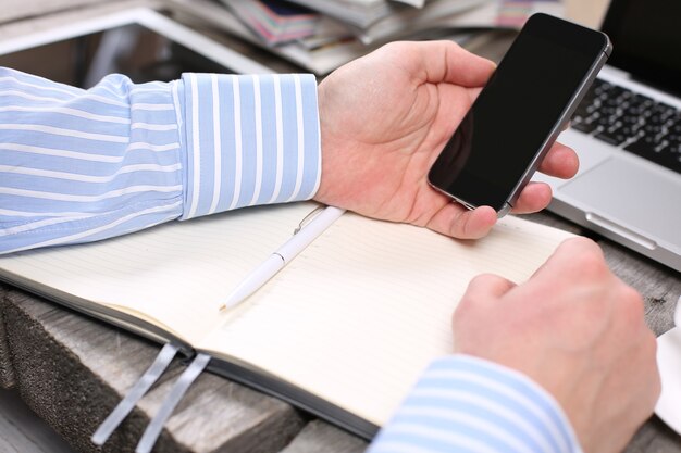 Mains tenant le téléphone sur la table en bois avec tablette