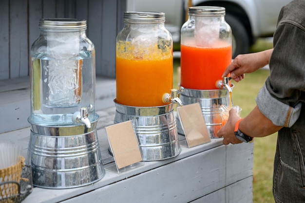 Les mains tenant un verre remplissent le jus du réservoir