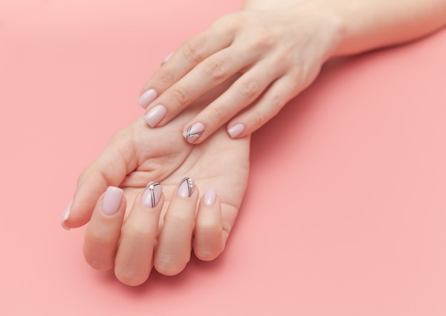 Mains tendres avec manucure nude parfaite sur rose pastel