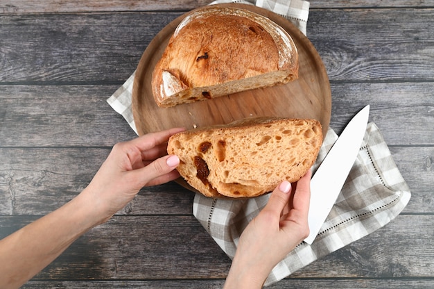 Mains tenir le pain fait maison coupé sur fond de bois