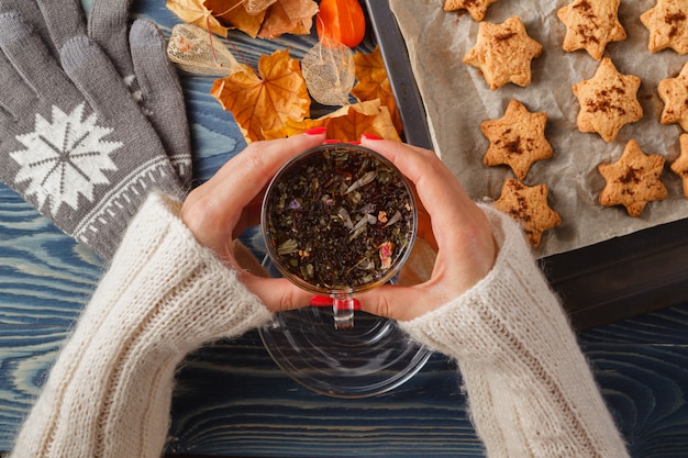 Mains tenir une tasse de thé en verre sur une table en bois