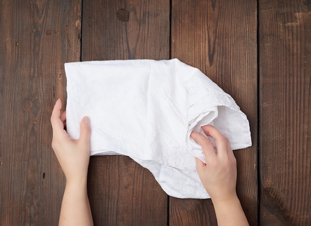 Mains tenir un torchon blanc sur une surface en bois marron