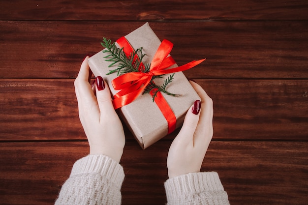 Mains tiennent belle boîte-cadeau sur un fond en bois. Tradition de Noël.