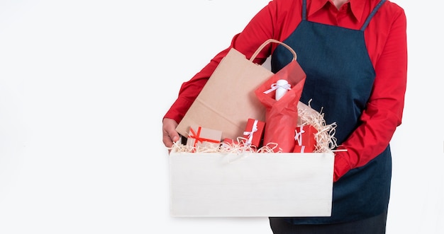 Les mains tiennent des cadeaux, un sac d'emballage et une bouteille de vin