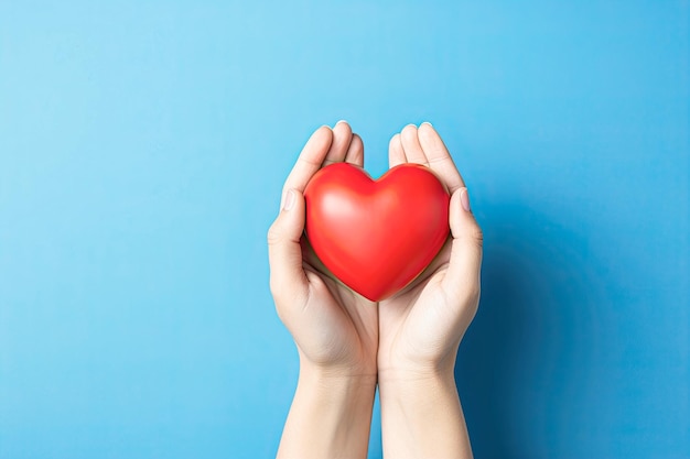 les mains tiennent un cœur rouge sur un fond bleu