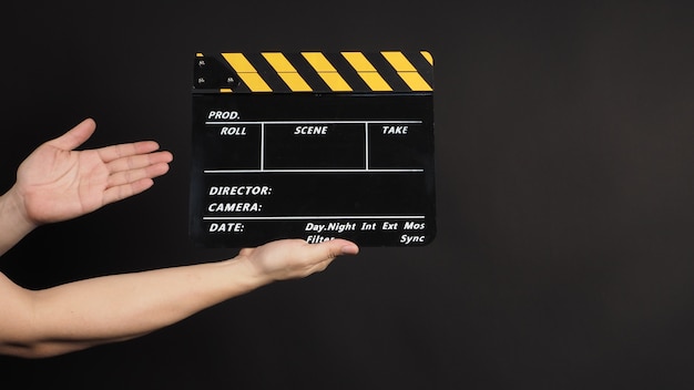 Les mains tiennent un panneau de clapet ou une ardoise de film. Il est utilisé dans la production vidéo et l'industrie cinématographique sur fond noir.