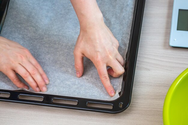 Photo les mains tiennent le papier de cuisson sur un plateau pour préparer un gâteau fait maison