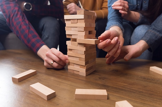 Les mains tiennent une tour de bâtons en bois, concept de travail d'équipe, jeu d'équipe. Photo de haute qualité