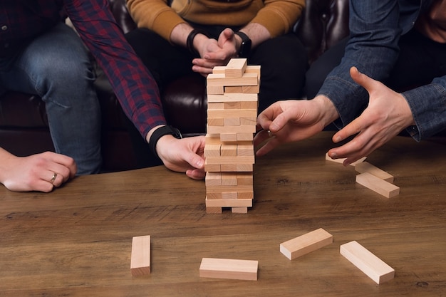 Les Mains Tiennent Une Tour De Bâtons En Bois, Concept De Travail D'équipe, Jeu D'équipe. Photo De Haute Qualité