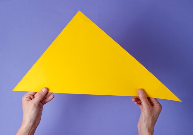 Les mains tiennent un triangle jaune sur un violet