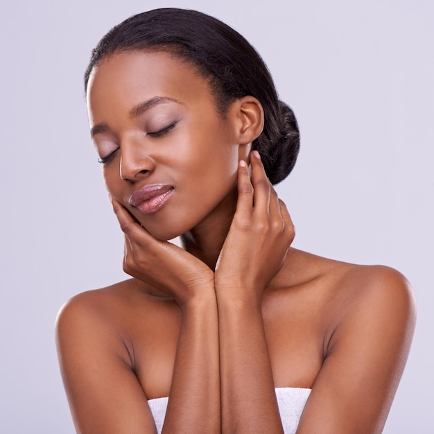 Mains touchant la peau et la femme noire avec beauté naturelle cosmétiques et bien-être avec maquillage sur fond blanc lueur saine soin de la peau et dermatologie satisfaction et calme pour le traitement en studio