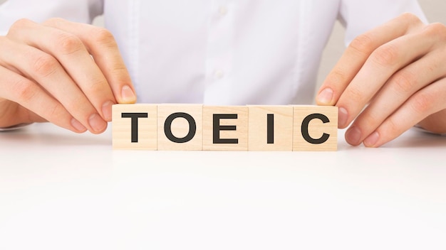 Les mains tournent le cube en bois et le mot TOEIC