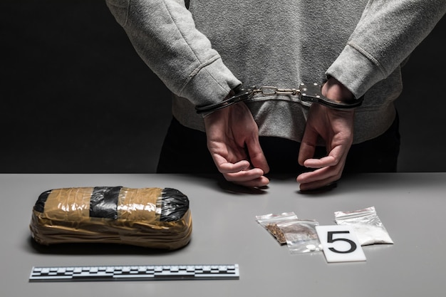 Les mains d'un trafiquant de drogue masculin sont menottées La lutte contre la drogue et le crime