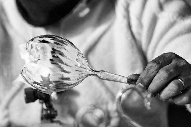 Photo mains de travail en verre tout en soufflant avec le feu une œuvre d'art