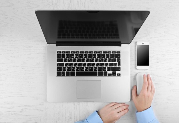 Mains travaillant au bureau avec un ordinateur portable sur un tableau blanc