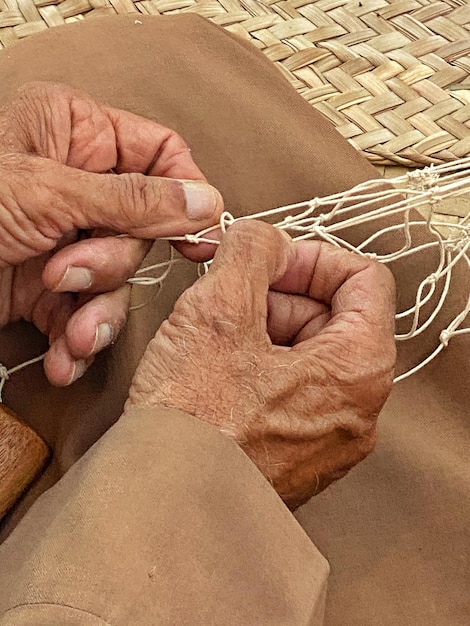 Les mains travaillent sur un panier tressé.