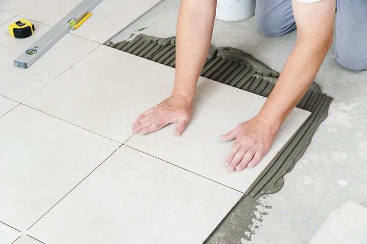 Mains de travailleur en appuyant sur les carreaux de céramique au sol
