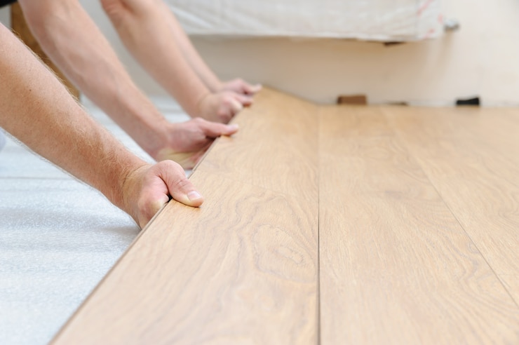 Mains de travailleurs serrant la rangée de planches dans le tableau de plancher