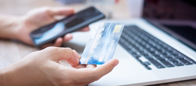 Mains utilisant une carte de crédit et des gadgets pour les achats en ligne