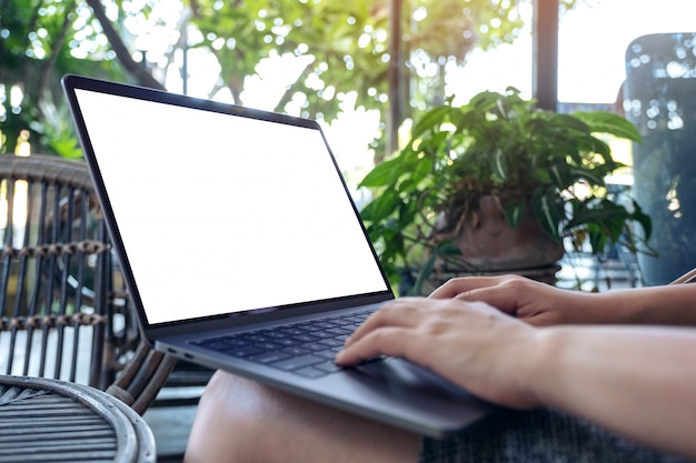 mains en utilisant et en tapant sur un ordinateur portable avec un écran de bureau blanc vierge alors qu'il était assis à l'extérieur