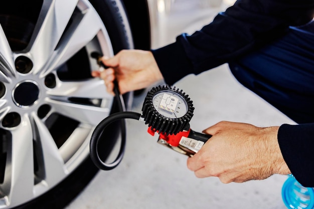 Mains vérifiant le service de voiture de pression des pneus