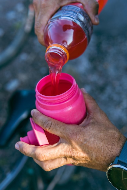 Mains versant une boisson pour sportifs dans une cantine