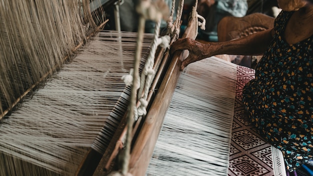 Les mains de la vieille femme en train de tisser, l’ancienne méthode de tissage.