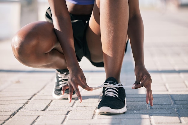 Les mains de la ville et de l'athlète attachent des chaussures pour commencer l'entraînement et l'exercice en plein air Fitness sportif et personne attachant des lacets sur des baskets pour se préparer à la course cardio et au jogging pour la santé et le bien-être