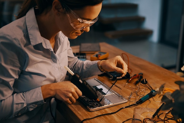 Et maintenant, pour tout sceller Photo recadrée d'une jolie jeune technicienne en informatique réparant un ordinateur portable dans son atelier