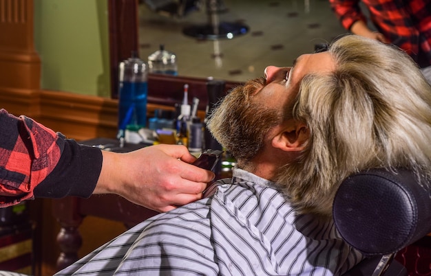 Maintenir la forme de la barbe Cultiver la barbe et la moustache Homme au salon de coiffure Salon de coiffure Coiffeur professionnel et client Couper la barbe en gros plan Améliorez votre expérience de coupe de cheveux Poils du visage