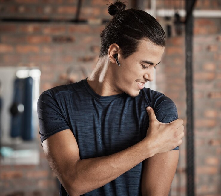 Photo maintien du muscle de l'épaule du bras et homme dans une salle de fitness et de bien-être heureux de l'objectif cible athlète sportif et jeune en bonne santé avec le sourire après l'entraînement et l'entraînement dans un club de santé