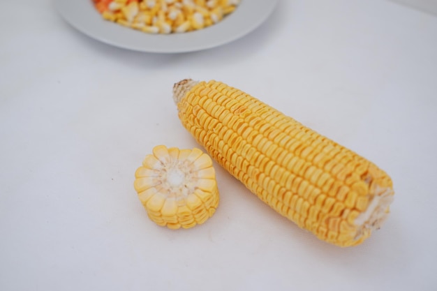 Photo maïs sur écorce et grains de maïs sur une assiette blanche sur un fond blanc