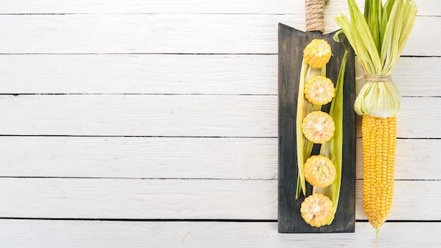 Maïs jaune frais sur une table en bois blanche. Des légumes. Vue de dessus. Copiez l'espace.