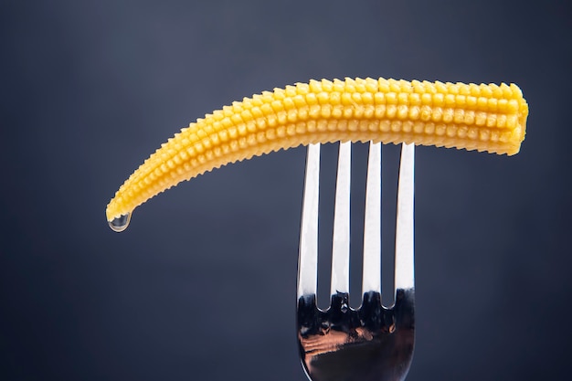 Maïs mariné sur une fourchette gros plan sur une sombre. nourriture et légumes