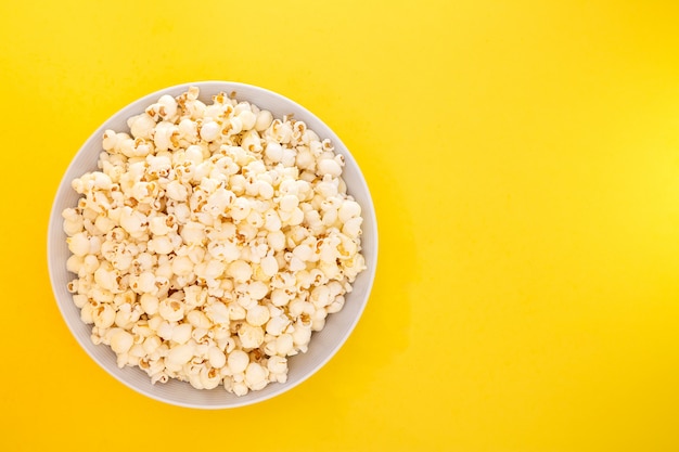 Maïs soufflé au beurre dans une tasse de pop-corn rouge, collation à la maison ou au cinéma