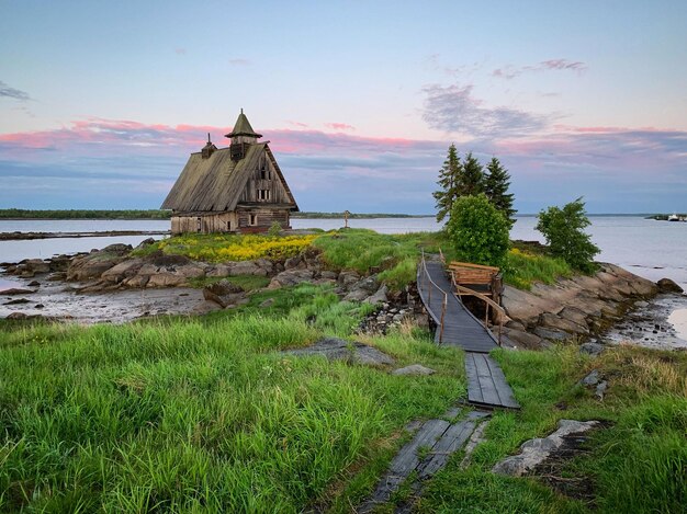 Une maison au bord d'un lac avec une maison en arrière-plan